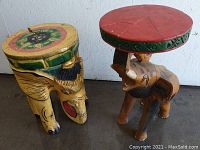 Photo showing two vintage wooden elephant stools with detailed paint and carved features.