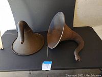 Front view of two metal antique phonograph horns showing curved and straight tube attachments with rust and wear.