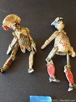 Two antique Royal Chesters painted metal toys posed on black background showing wear and paint chipping.