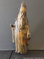 Front view of the antique cast iron Asian wiseman statue showing figure in traditional robes with a tall hat and long beard.