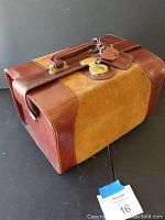 Side view of vintage leather travel box showing locking mechanism with key inserted, leather texture, and handle attachment.