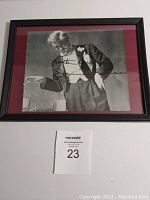 Full view of framed magazine page with red matte and black frame on white background