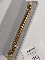 Full length view of bracelet laid in box showing gold Cuban link chain and box clasp.