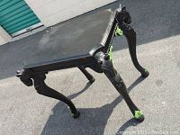 Full view of the antique side table showing the black painted top and the four horse head carved legs with green accent feet.