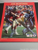 Full view of poster with Joe Montana playing football, wearing red 49ers uniform #16, with autograph on the lower right area.