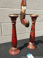 Frontal view of entire wooden pendulum toy showing figure mounted on metal rod between two painted wooden columns.