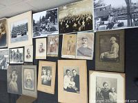 Overview of antique photographs laid out on table, showing variety of portraits and group photos in black and white.
