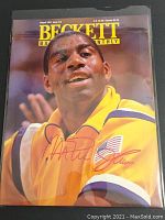 Front cover of Beckett Basketball Monthly magazine featuring Magic Johnson in a yellow jacket with autograph in red ink.