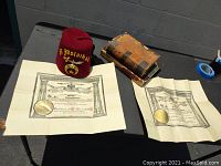 Photo showing entire lot including two antique books, two certificates, and a red fez hat