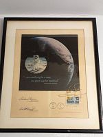 Black-framed print with cream mat showing Earth, astronaut, quote, stamp and signatures.