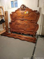 Headboard and footboard leaning against basement wall with side rails on floor