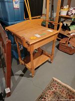 Side-angle view of the vintage wood washstand showing the tabletop, legs, and lower shelf.