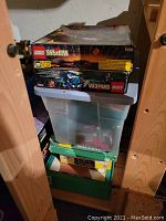 Stacked LEGO System boxes atop plastic bin and green Meccano box