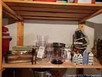 Shelf with clear glass vases, copper teapot, brass tray and candlestick, Blue Delft KLM ceramic bottles shaped as Dutch houses.