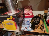 Photo showing ice bucket, manual ice maker box, decorative soap set box, blue and white china vases partially visible, and dark green glass dish with costume jewelry pieces on top.