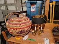 Woven basket and metal two candle style lamp on wooden table