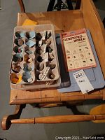 Top-down image of plastic container holding an egg carton with multiple labeled stone specimens, plus an educational gemstone guide book