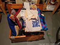 Lot of folded wool blankets, assorted linen napkins, towels laid flat and stacked in wooden box.