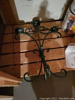Cast aluminum 3-arm candelabra sitting on shelf