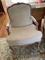 Front view of Berger style occasional chair showing ultrasuede light beige upholstery and carved wooden frame
