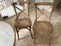 Front view of two wooden Restoration Hardware Madeleine chairs with cane seats. Displaying minor wear, one cane seat slightly damaged.
