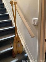 Photo of two large Langford wooden paddles and one small dark wood miniature paddle displayed on carpeted stairs.
