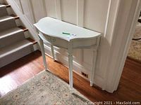 Demilune table placed against wall near staircase showing side and front angles