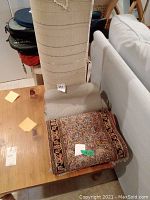 Rolled up silk carpet runner with visible floral design in traditional Kashmiri style and colors, placed on wooden table.