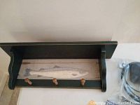 Full view of wood shelf showing painted fish on back panel and coat hooks