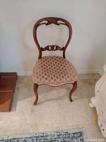 Front view of vintage wooden chair with curved backrest and upholstered patterned seat.