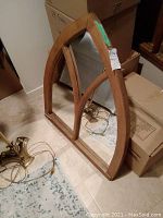 Mirror leaning against boxes showing full arched wood frame with vertical dividers.