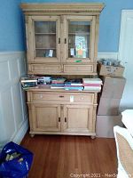 Full front view of two-piece pine cabinet with books on lower shelf