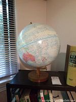 Front angle showing globe positioned to display Australia and surrounding Pacific regions, mounted on wooden swivel stand with round base.