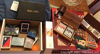 Overview of the lot showing Mahjong box, multiple decks of cards in various cases, dice cup, and books including the Hoyle casino guide.