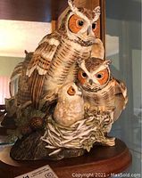 Front angled view of the great horned owls figurine showing three owls on a wood base.