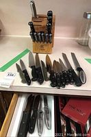 Photo of J.A. Henckels knife block filled with knives alongside additional knives laid out on a countertop.