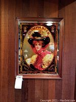 Frontal view of framed Olympia Beer mirror showcasing the vintage portrait of a woman in a hat and red scarf with ornate gold and black border.