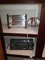 Shelf with Noma quartz fan heater, Creative fan heater with light, and separate silver dome light with cord