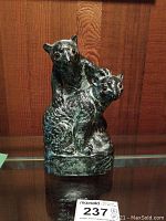 Full view of the stone carved sculpture showing two bears with detailed carving and amber eyes.