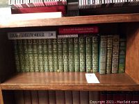 Shelf with the complete works of Charles Dickens in green hardcover binding with gold embossing along with two other books on top: Legal Problem Solver and McGraw-Hill Handbook of English.