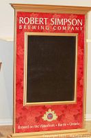 Full view of large rectangular framed chalkboard sign with red background, white lettering, and a black chalkboard center.