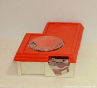Red and white plastic Hot Wheels Speedometer toy, top view showing clear plastic dial and side opening.