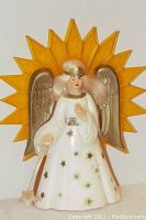 Front view of plastic Christmas tree angel with gold wings and yellow sunburst halo