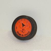 Front view of the Pow-R-Puck device showing the measurement dial and branding.