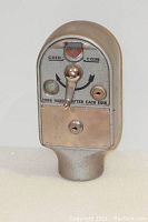 Front view of the vintage heavy metal parking meter showing coin slots, turn handle, and locks.