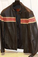 Front view of black leather jacket with red and beige stripes, zipper front and collar snap button.