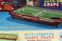 Photo showing the full green felt craps table layout with brown molded plastic edges and dice cup.