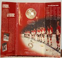 Front inside view of the tri-fold folder housing the commemorative Team Canada hockey sterling silver dollar coin by the Royal Canadian Mint. Shows players lined along the boards on the ice rink with French and English text about the coin and event.