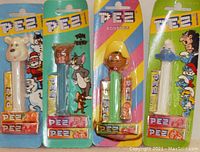 Photo of four PEZ dispensers in packaging: IceeBear, Tuffy, Speedy Gonzales, and Smurf, each with candy rolls included.