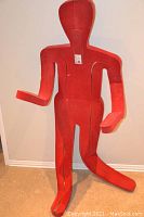 Front view of red flexible mannequin with one leg bent and both arms raised to the sides showing articulation points.